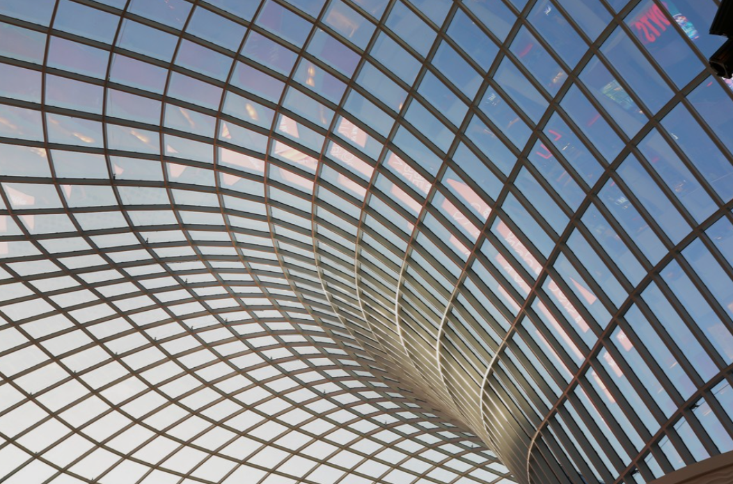 Detail of an engineered glass-and-steel lattice roof structure, natural light